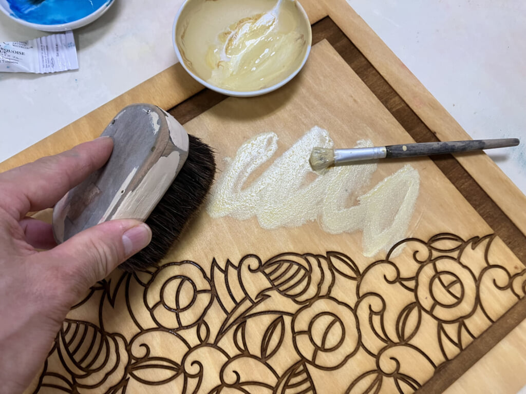 制作工程の画像。椿の柄が彫られた版木に絵の具が塗られている。