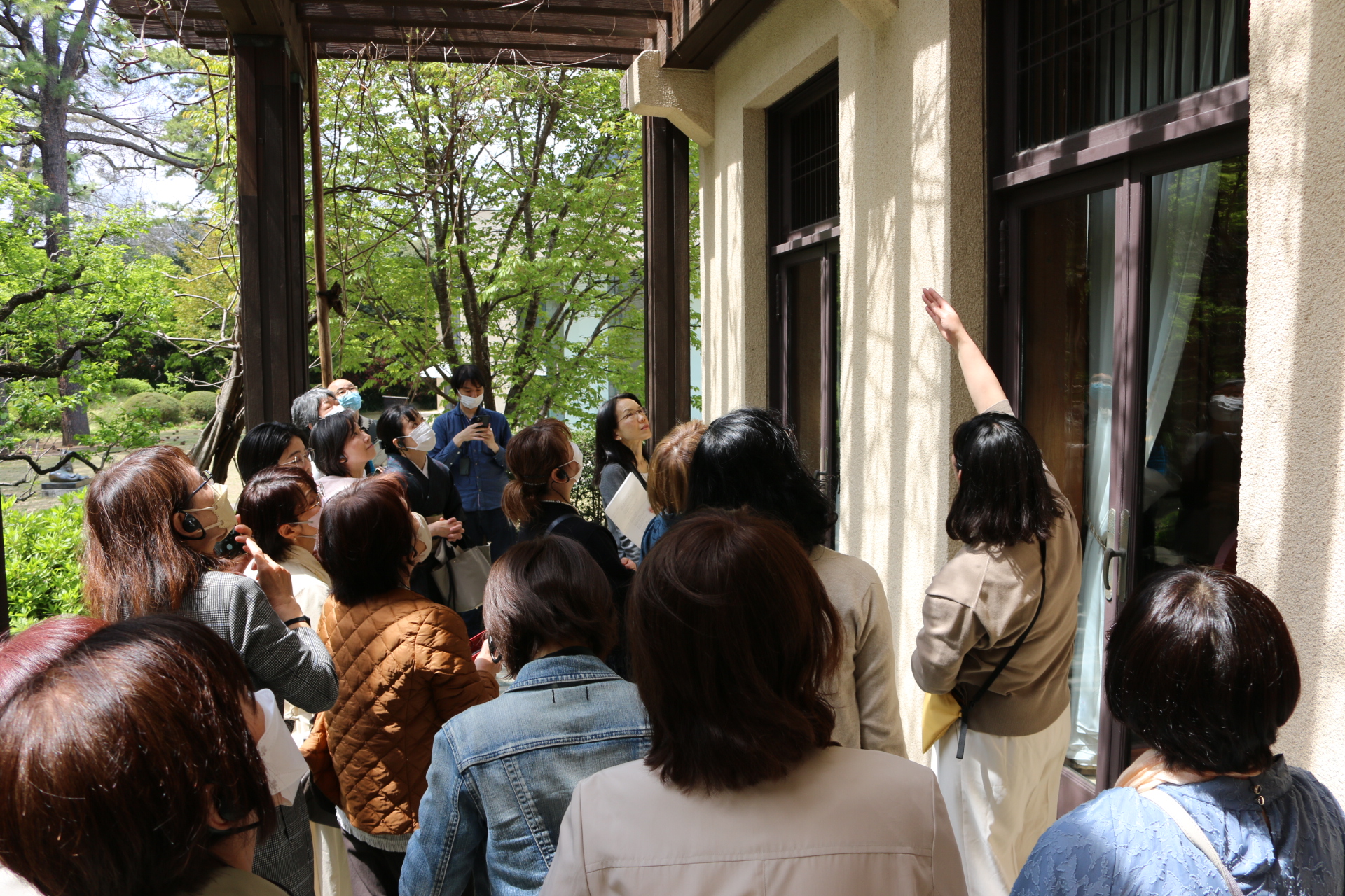 ツアーの様子。屋外のパーゴラで修復の説明行う学芸員と参加者。