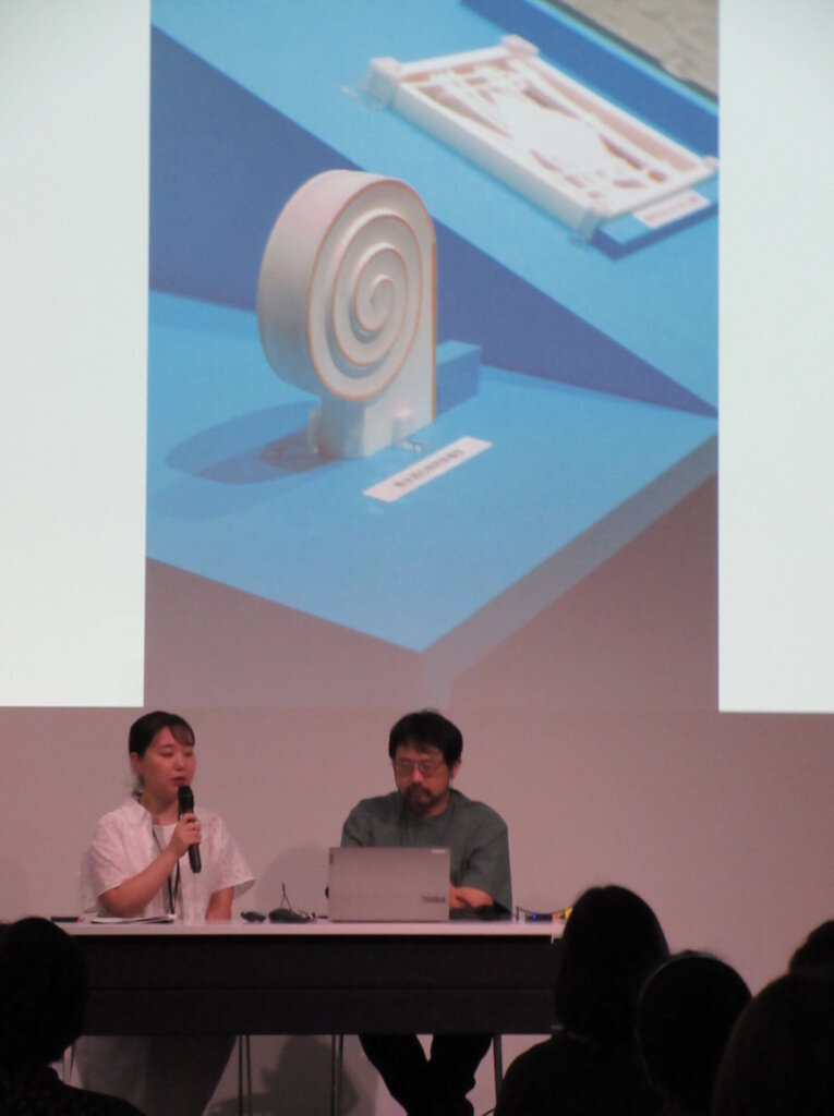 香水塔の照明部模型について解説している様子