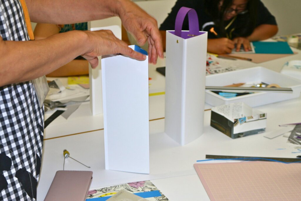 紋切りした画用紙を三角柱の白い紙の中にセットする様子